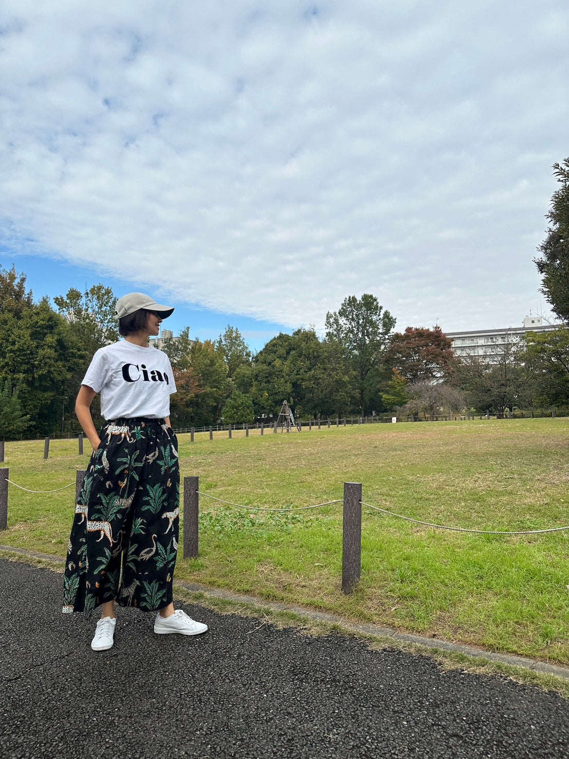 黒いジャングル柄のワイドパンツを履いた女性モデルが公園にたっている写真